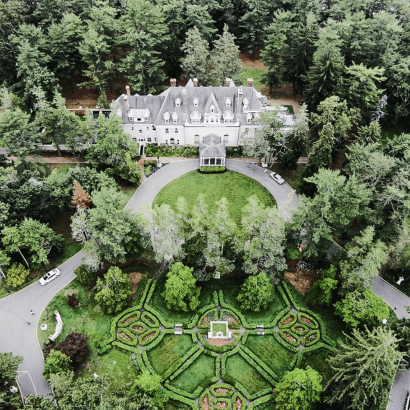 Aerial view of building surrounded by trees and a road