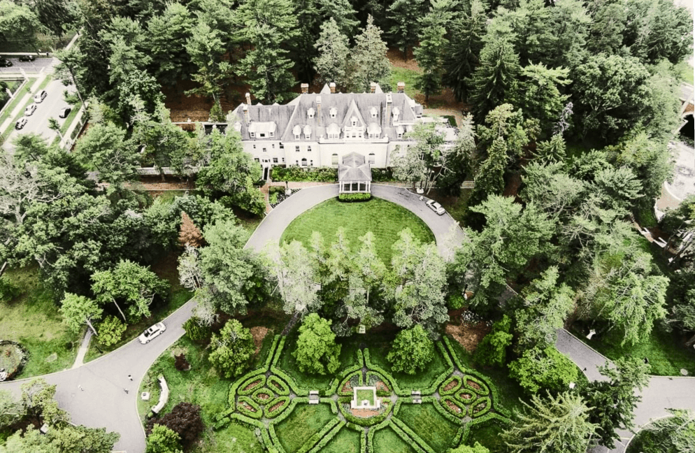 Aerial photo of campus showing large building surrounded by trees and a road