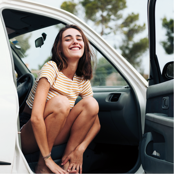 Young woman smiling and leaning out of passenger seat of a parked car